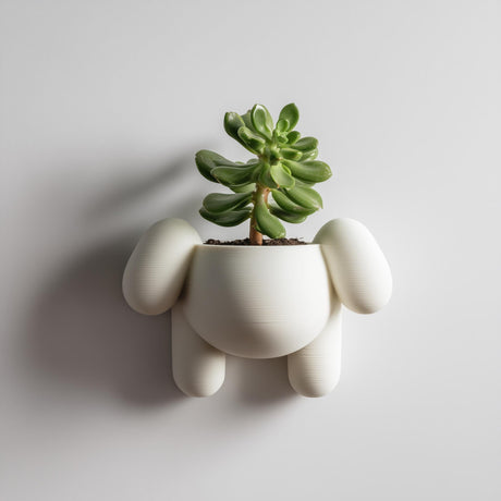 3D printed puppy-shaped wall planter pot in matte cream PLA mounted on a neutral wall, holding a small green succulent plant.