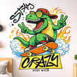 A vibrant, cartoon-style illustration of a green T-Rex dinosaur riding an orange skateboard. The T-Rex wears yellow sunglasses, a red cap, and red sneakers, making peace signs with both hands. It is surrounded by orange flames and blue clouds with the words "STAY CRAZY" in bold black graffiti lettering.
