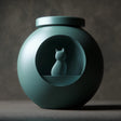 3D printed orb-shaped pet ashes urn with a circular recessed window featuring a small cat figure inside, fitted lid on top, studio-style background.