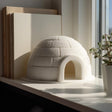 3D printed white igloo shelf decor with textured brick pattern displayed on a modern desk beside books and indoor plants.