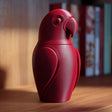 3D printed parrot memorial urn with removable lid displayed on a wooden shelf in warm indoor lighting.