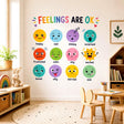 Colorful children’s feelings chart reading “FEELINGS ARE OK,” with twelve expressive faces labeled happy, sad, sleepy, surprised, frustrated, calm, shy, excited, bored, silly, worried, and sick.
