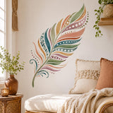 Large watercolor feather in muted teal, sage, coral, mustard, dusty rose, and olive, with curved bands, dots, and geometric patterns on a white background.