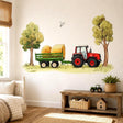 Watercolor-style farm scene with a red tractor pulling a green trailer loaded with large golden hay bales, framed by two leafy trees with grass below and a small bird flying overhead.