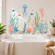 Pastel underwater scene with two floating jellyfish, four small fish, bubbles, branching coral, seaweed, sea sponges, seashells, stones, and a starfish in aqua, blue, coral, cream, and green tones.