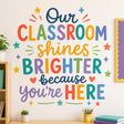 Colorful classroom quote reading “Our Classroom Shines Brighter Because You’re Here” in coral, teal, yellow, lavender, green, blue, and navy lettering, surrounded by small stars, hearts, sparkles, and decorative lines.