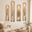 Four tall arched beige wall niches with soft spotlight details, each holding a cream ceramic vase with dried grasses, delicate branches, pale round leaves, or a fan-shaped palm leaf.