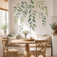 Watercolor-style cascading branches with sage, olive and pale yellow-green leaves arranged along an upper wall.