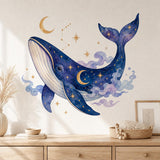 Deep blue watercolor-style whale with gold-colored stars and constellation lines, surrounded by moons and lavender clouds.