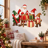 Christmas wall sticker with Santa and three cheerful gnomes wrapping red, green and gold gifts at a small table.