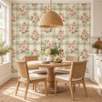 Blush pink rose bouquets and green leaves over cream and sage green plaid wallpaper in a dining area beside a white kitchen.
