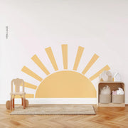 Minimalist sun wall decal in soft yellow tones for nursery decor with wooden toys and a cozy rug.