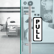 Clear 'PULL' sticker on stylish glass door handle in modern living space.