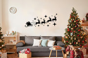 Santa sleigh with reindeer silhouette decal above cozy sofa and Christmas trees for festive home decor.